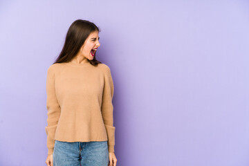 Young caucasian woman isolated on purple background shouting very angry, rage concept, frustrated.
