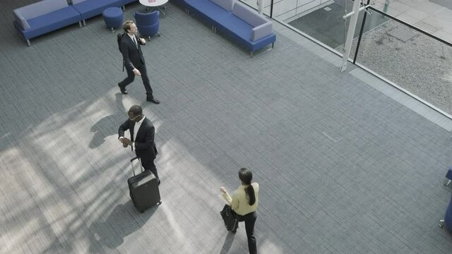 Business man walking in airport terminal lounge and checking departure time on smart watch