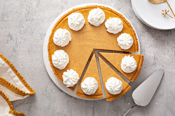 Pumpkin pie with whipped cream with slices taken out