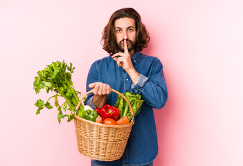 Young man picking organic vegetables from his garden isolated keeping a secret or asking for silence.