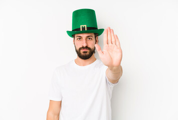 Young caucasian man wearing a saint patricks hat isolated standing with outstretched hand showing stop sign, preventing you.