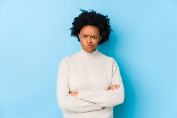 Obraz na płótnie Canvas Middle aged african american woman against a blue background isolated frowning face in displeasure, keeps arms folded.