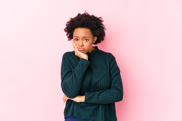 Fototapeta na wymiar Middle aged african american woman against a pink background isolated who is bored, fatigued and need a relax day.