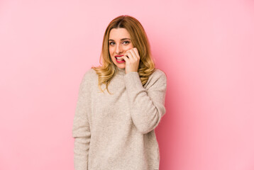 Young blonde cute woman wearing a sweater isolated biting fingernails, nervous and very anxious.