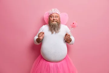 Fototapeten Plump bearded man has image of magic fairy, clenches fist, happy about his abilty to make things disappear, pretends being supernatural being, plays with kids on party, uses power for invisibility © Wayhome Studio