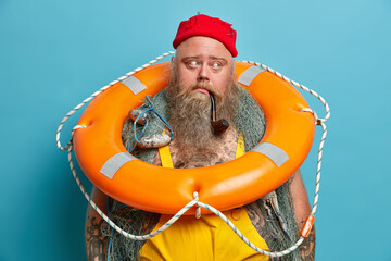 Thoughtful mariner carries inflated ring buoy on neck, ready to rescue people at sea, has thick...