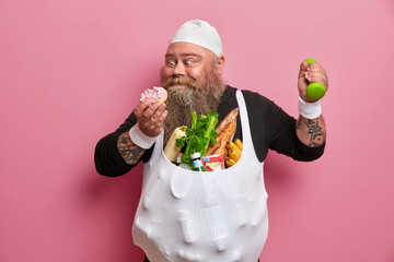 Funny bearded fatso guy resists temptation eat sweet appetizing doughnut, tries to lead healthy...