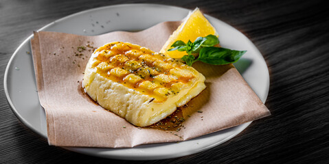 Halloumi cheese frying with orange in plate on black wooden table