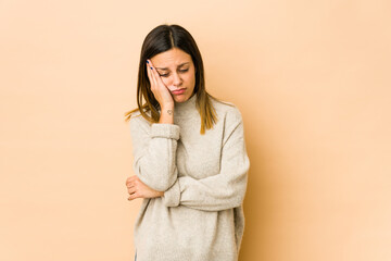 Young woman isolated on beige background who is bored, fatigued and need a relax day.