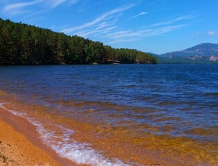 Stunning views of the lake and mountains with yellow  sand, prosaic water and blue skies
