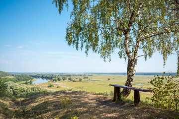 Place for having a rest on the cliff on the bench under the birch tree with a marvelous view to the river