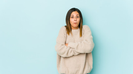 Young woman isolated on blue background shrugs shoulders and open eyes confused.