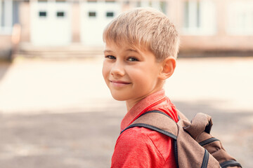 Portrait of little boy going to school, looking back to the camera