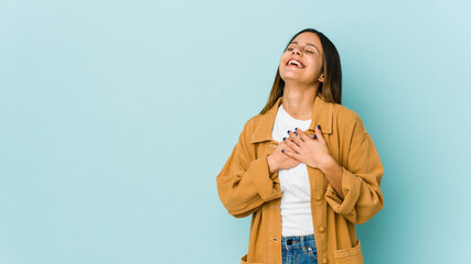 Young woman isolated on blue background laughing keeping hands on heart, concept of happiness.