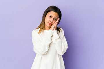 Young woman isolated on purple background yawning showing a tired gesture covering mouth with hand.