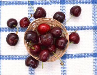 Handful of a red cherry in basket on tablecloth background