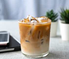 Close-up of afternoon coffee. top view a glass of ice coffee with milk with tablet and smartphone the white table refreshing  cold drink in the summer  relaxing hour with copy space