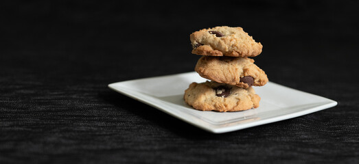 cookies on a white plate, dark background, chocolate chip cookies, stacked cookies