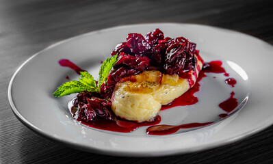 Halloumi cheese frying with cherry in plate on black wooden table