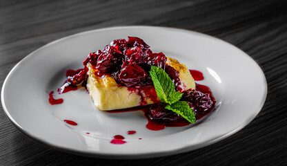 Halloumi cheese frying with cherry in plate on black wooden table