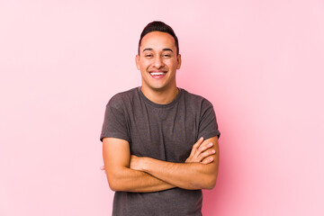 Yooung latin man posing in a pink backgroundlaughing and having fun.