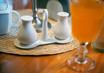 salt and pepper porcelain shakers standing in a restaurant on a wooden table