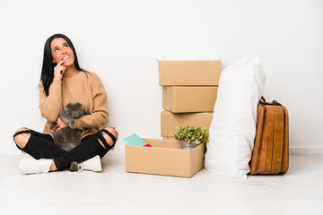 Woman moving home isolated on white background relaxed thinking about something looking at a copy space.