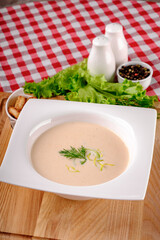 A bowl of creamy potato soup with crackers bread on white plate in italian restaurant background, top view. Vegetable cream soup. Italy food. Close up. space