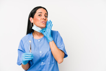 Dentist woman isolated on white background is saying a secret hot braking news and looking aside