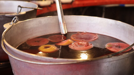 Mulled wine cooked on a fire outside. Vitamins in a winter drink. Street eatery at the Christmas market in winter. Hot mulled wine. Dense steam over cauldrons of hot wine.