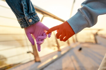Safe touch. Close up of hands of lesbian couple. Two girls holding their hands, wearing protective...