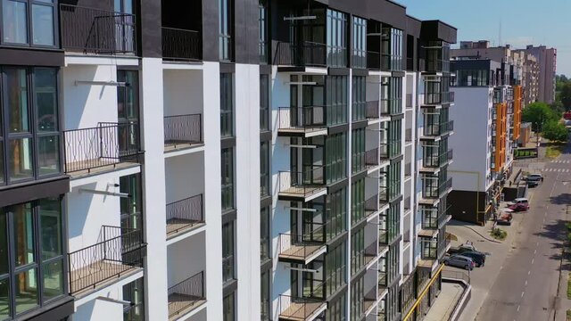 New architecture in the city. High-raise apartment buildings near the road. Modern design of multistorey building. Drone flight.