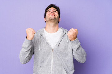 Fototapeta premium Young man isolated on purple background celebrating a victory, passion and enthusiasm, happy expression.