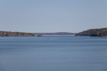 Peacefull landscape with boat in the lake Malaren and forest on background, Sweden.