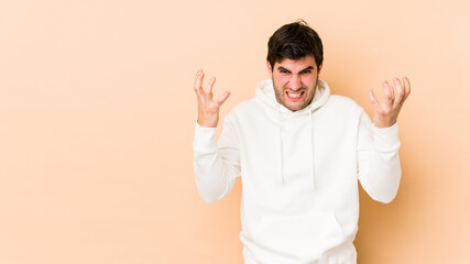Fototapeta premium Young man isolated on beige background screaming with rage.