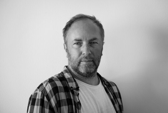 Adult well-groomed man in a plaid shirt, on a white background. Black and white photography.