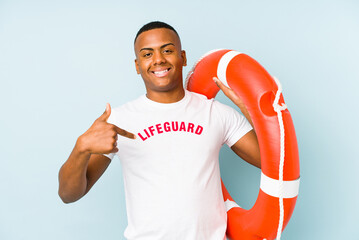 Young latin life guard isolated on blue background person pointing by hand to a shirt copy space,...