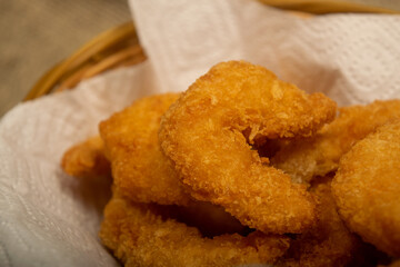 Atlantic shrimps fried in batter on a white paper napkin in a wicker basket. Close up.