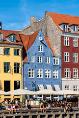 Fototapeta premium Detail of the touristic Nyhavn pier with people having relax, colorful buildings and boats in Old Town of Copenhagen, Denmark