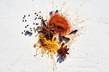 Close-up star anise, cloves on  various powder spices of chili, turmeric, and sesame seeds on a...