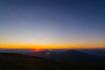 The first or last rays of the sun on a mountain pass. Morning and evening in nature. Colorful sunset and sunrise over the mountain hills. Carpathians in summer and autumn.