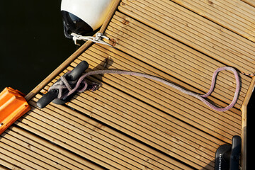 Yacht rope detail image on figure eight cleat hitch on wooden deck. Close up of boat rope tied with free space for text. Maritime theme.
