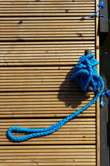 Yacht rope detail image on figure eight cleat hitch on wooden deck. Close up of boat rope tied with free space for text. Sailboat winch.