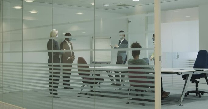 Business people meeting in boardroom wearing protective face mask and keeping social distance
