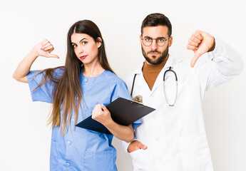 Young doctor man and a nurse isolated showing a dislike gesture, thumbs down. Disagreement concept.