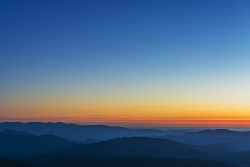 The first or last rays of the sun on a mountain pass. Morning and evening in nature. Colorful sunset and sunrise over the mountain hills. Carpathians in summer and autumn.