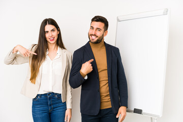 Young caucasian business couple isolated person pointing by hand to a shirt copy space, proud and confident