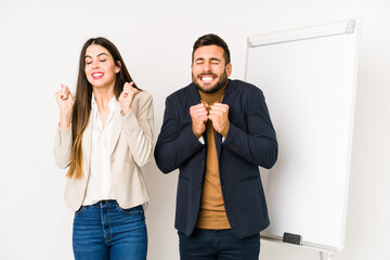 Young caucasian business couple isolated raising fist, feeling happy and successful. Victory concept.