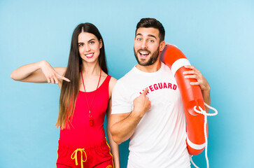 Young lifeguard couple isolated person pointing by hand to a shirt copy space, proud and confident