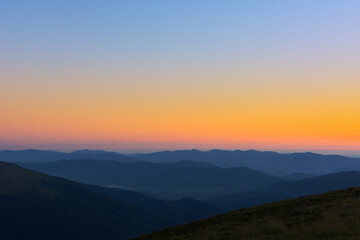 The first or last rays of the sun on a mountain pass. Morning and evening in nature. Colorful sunset and sunrise over the mountain hills. Carpathians in summer and autumn.